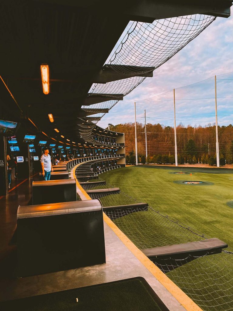 Panoramic view of a lush green golf course at Topgolf Rogers. Smooth