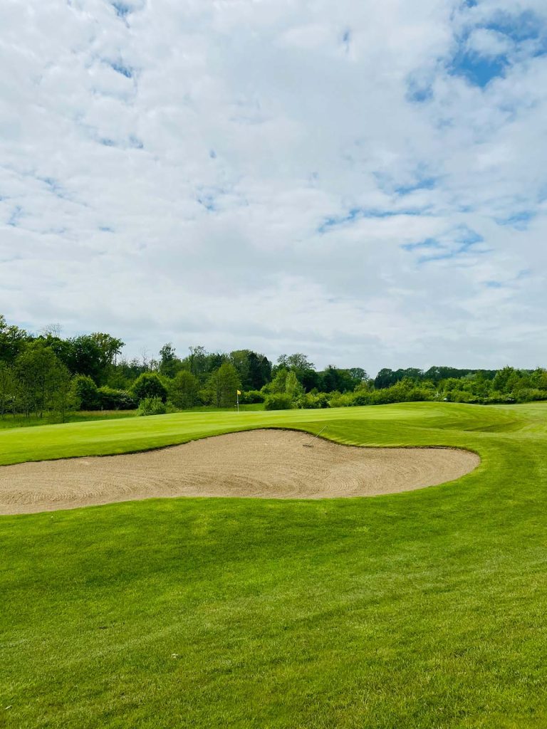 Panoramic view of a lush green golf course at Whippoorwill Golf Course. Smooth