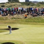 The best golf course in action: golfers teeing off on a challenging hole with a backdrop of rolling hills.