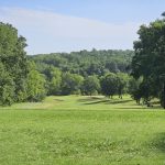 Panoramic view of a lush green golf course at Bella Vista Country Club Golf Course and Clubhouse. Smooth