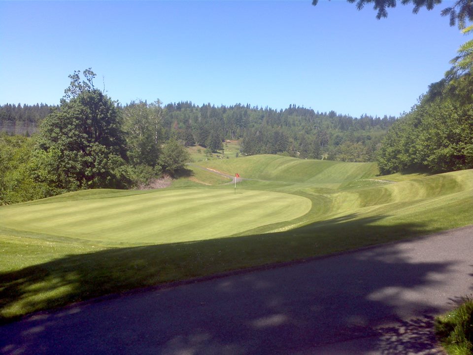 Panoramic view of a lush green golf course at Coos Golf Club. Smooth