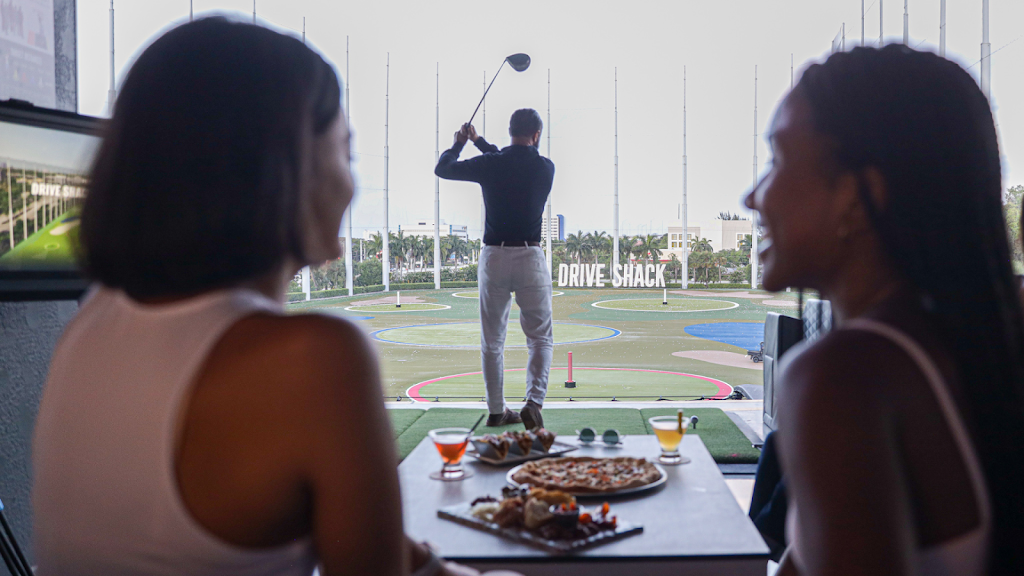 Panoramic view of a lush green golf course at Drive Shack. Smooth