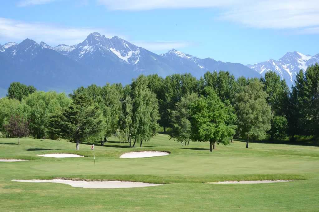 Panoramic view of a lush green golf course at Mission Mountain Golf Club. Smooth