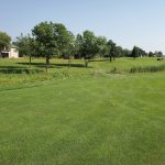 Panoramic view of a lush green golf course at NuMark Golf Course. Smooth