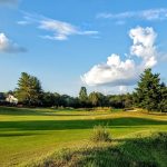 Panoramic view of a lush green golf course at Pebble Creek Golf Course. Smooth