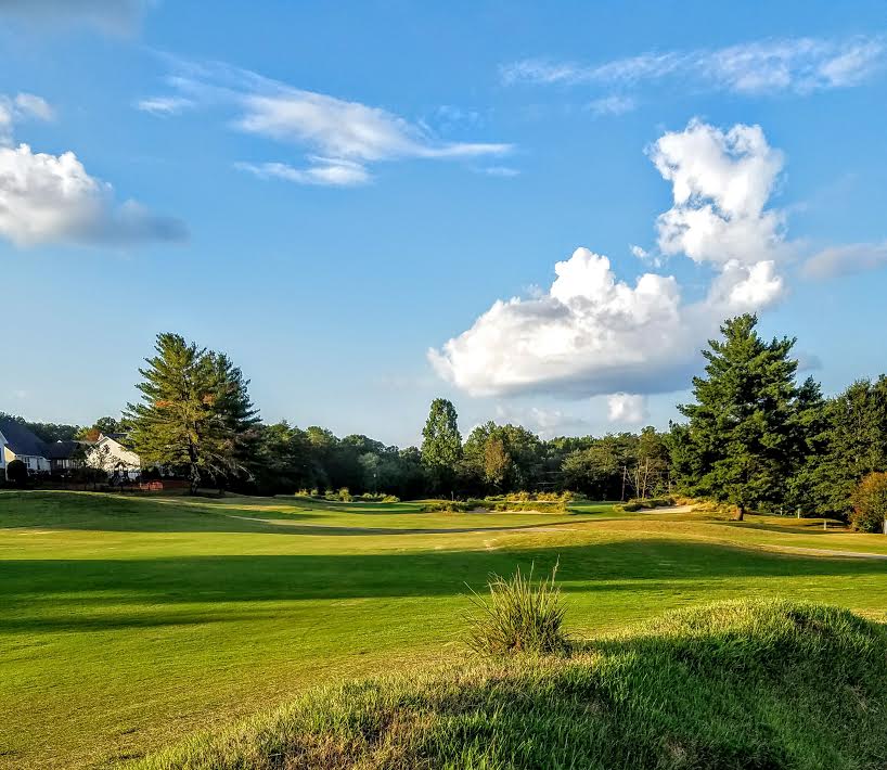 Panoramic view of a lush green golf course at Pebble Creek Golf Course. Smooth