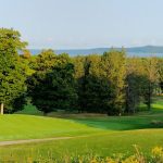 Panoramic view of a lush green golf course at Pinecroft Golf Course. Smooth