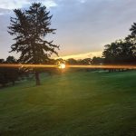 Panoramic view of a lush green golf course at Potowomut Golf Club. Smooth