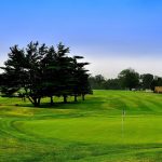 Panoramic view of a lush green golf course at Rock Manor Golf Course. Smooth