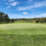 Panoramic view of a lush green golf course at Silver Bay Golf Course. Smooth