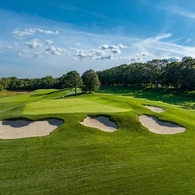 Panoramic view of a lush green golf course at Spy Ring Golf Club. Smooth