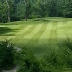 Panoramic view of a lush green golf course at Sunset Ridge Golf Links. Smooth