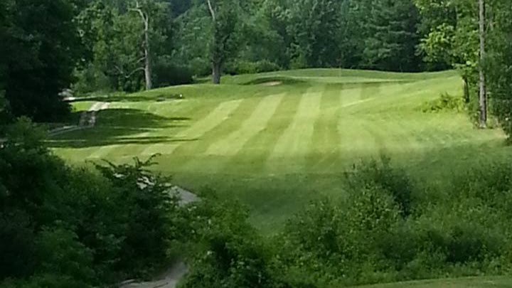 Panoramic view of a lush green golf course at Sunset Ridge Golf Links. Smooth