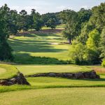 Panoramic view of a lush green golf course at The Chimneys Golf Course. Smooth