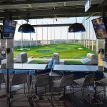 Panoramic view of a lush green golf course at Topgolf Nashville. Smooth