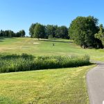 Panoramic view of a lush green golf course at Waters Edge Golf Course. Smooth