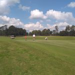 Panoramic view of a lush green golf course at Whispering Pines Golf Course. Smooth