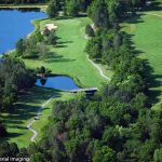 Panoramic view of a lush green golf course at Woodland Hills Golf Course. Smooth